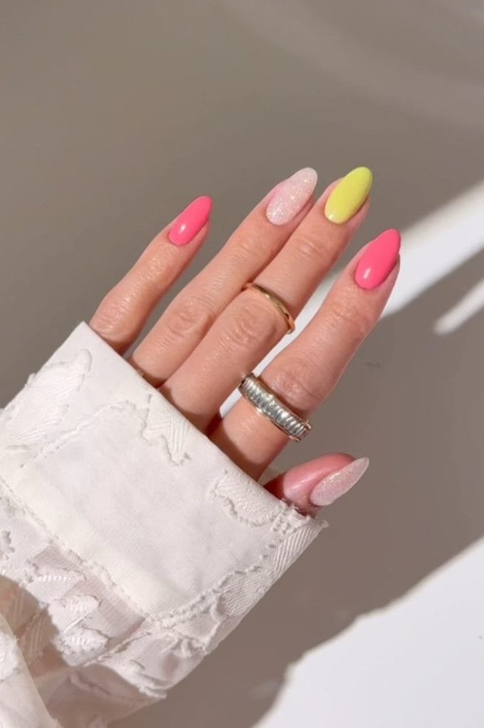 almond August nails with hot pink, shimmery soft pink, and bright yellow polish