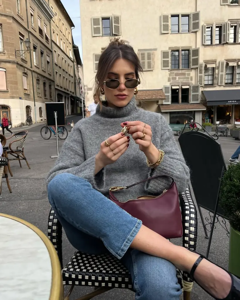 fall outfit with grey oversized turtleneck, straight-leg jeans, gold jewelry and burgundy leather shoulder bag
