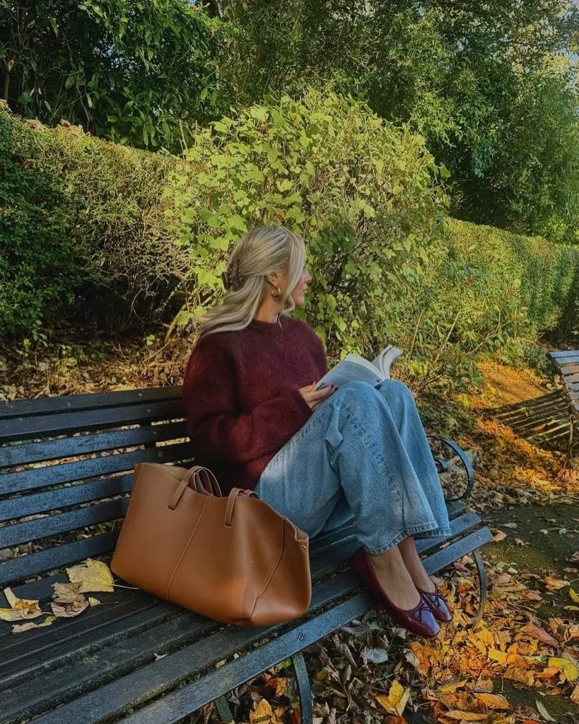 Casual fall outfit with burgundy sweater, light wash jeans, burgundy loafers, tan leather tote bag