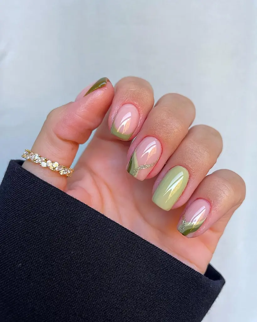 Short fall nails with green French tips, sheer pink base, and gold glitter line accents