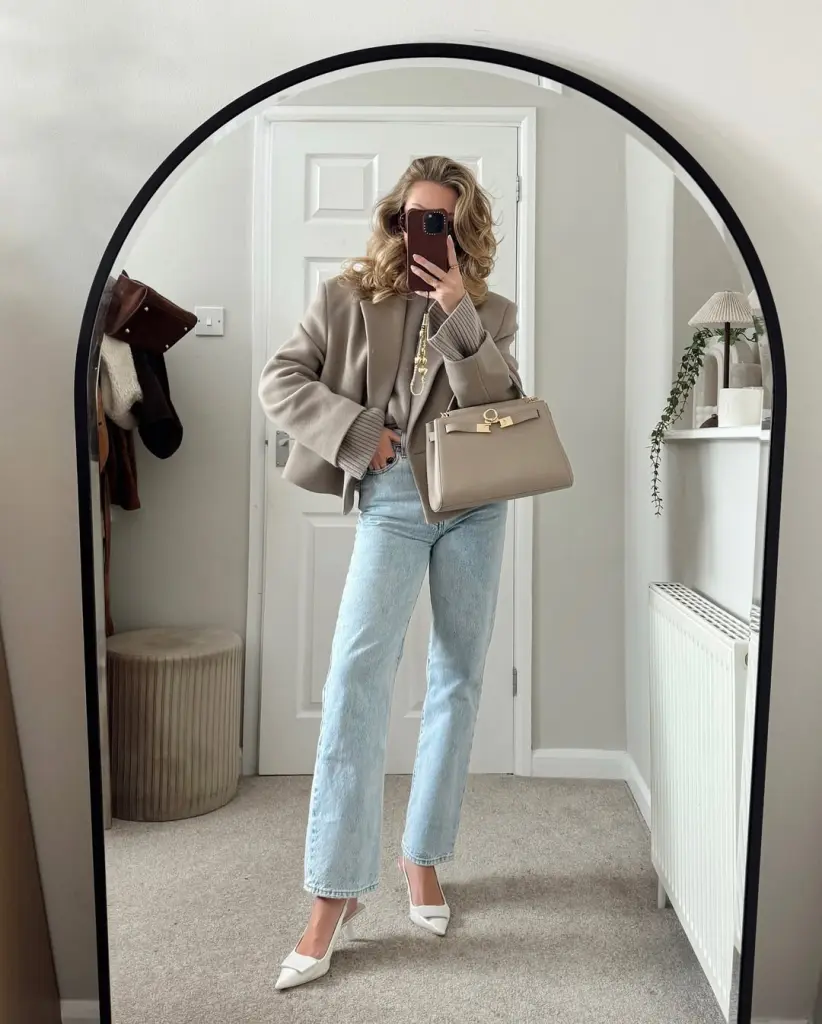 neutral fall outfit with beige oversized blazer, ribbed knit sweater, light wash straight-leg jeans, white pointed pumps and beige structured handbag
