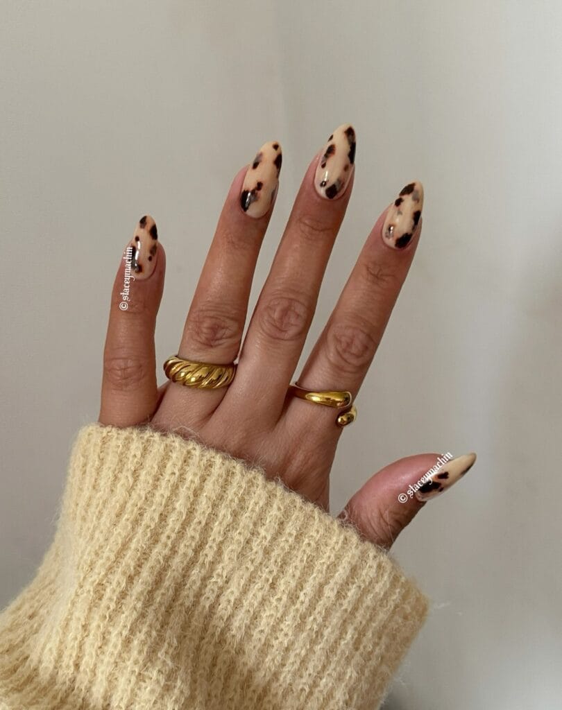 Cream almond fall nails with scattered brown and dark patches
