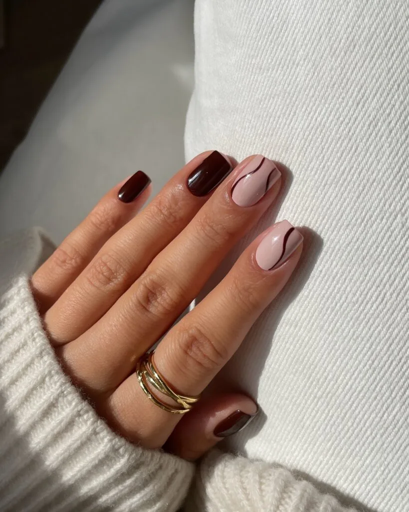 Short simple fall nails in chocolate brown and pale blush with thin curved brown line art.