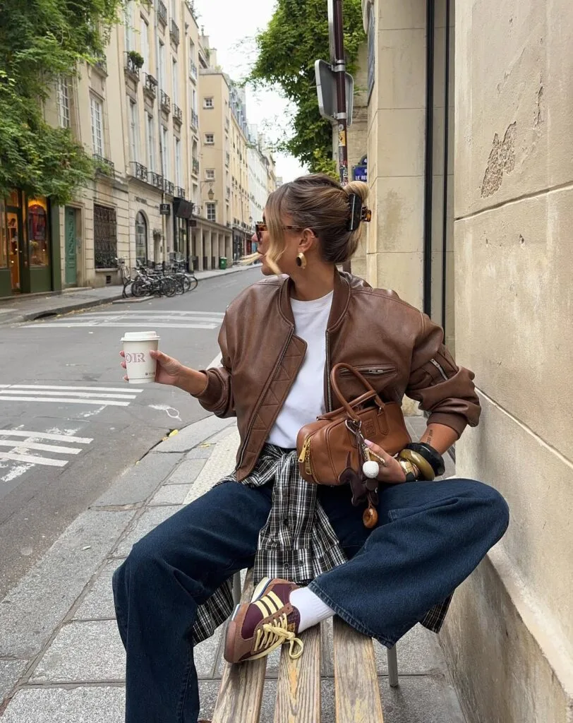 Everyday fall outfit with brown leather bomber, white tee, dark wide-leg jeans, and plaid shirt tied at the waist
