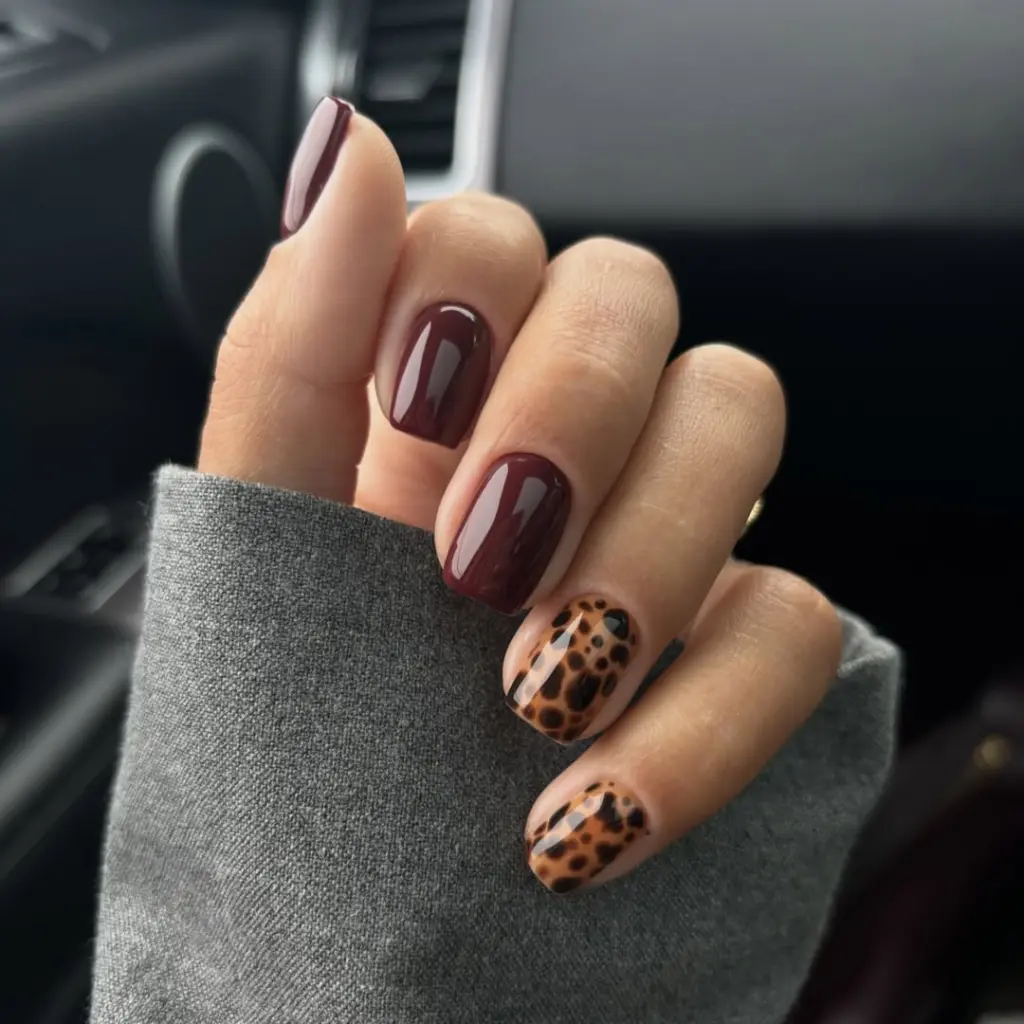 Short fall nails with burgundy polish and leopard print accent nails in brown and black spots