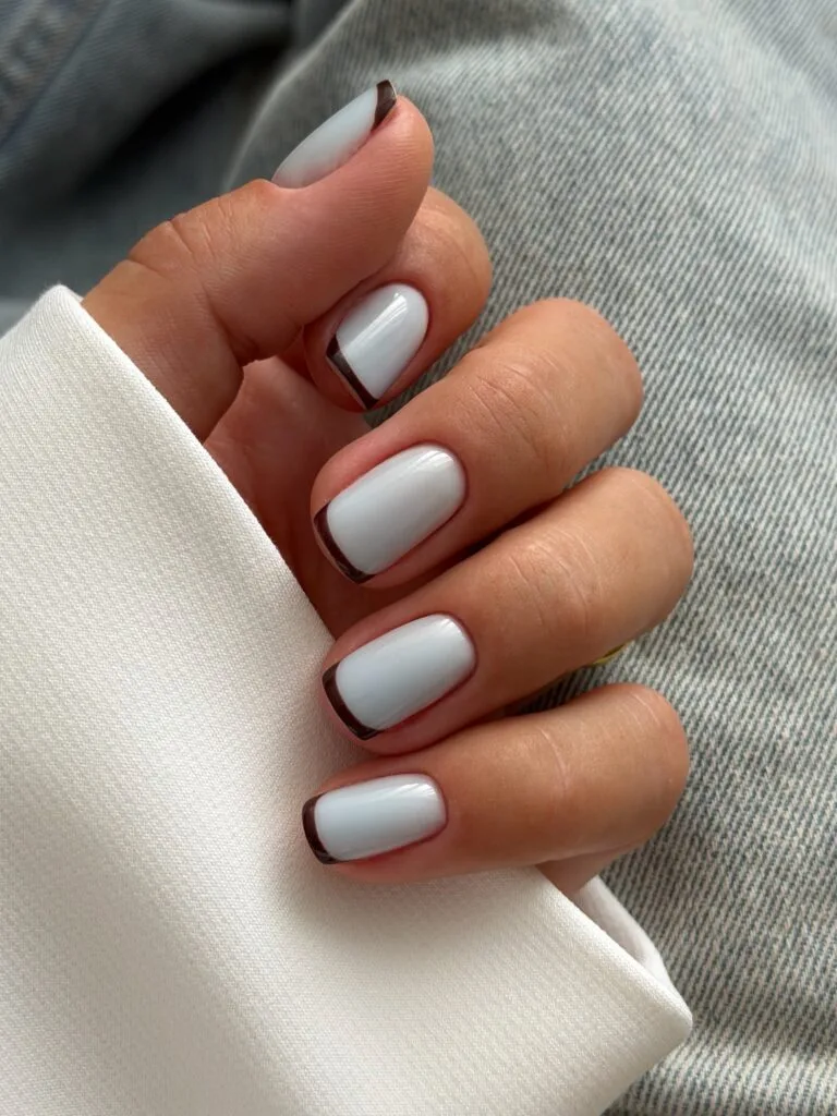 Short square nails with glossy pale blue bases and thin chocolate brown French tips