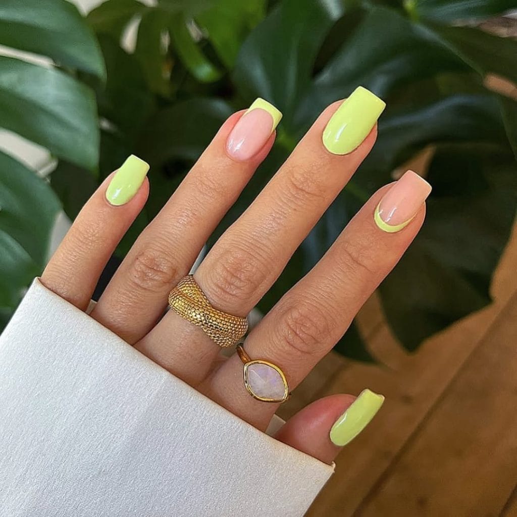 Medium square August nails with neon yellow polish and nude base featuring French tips and reverse French designs