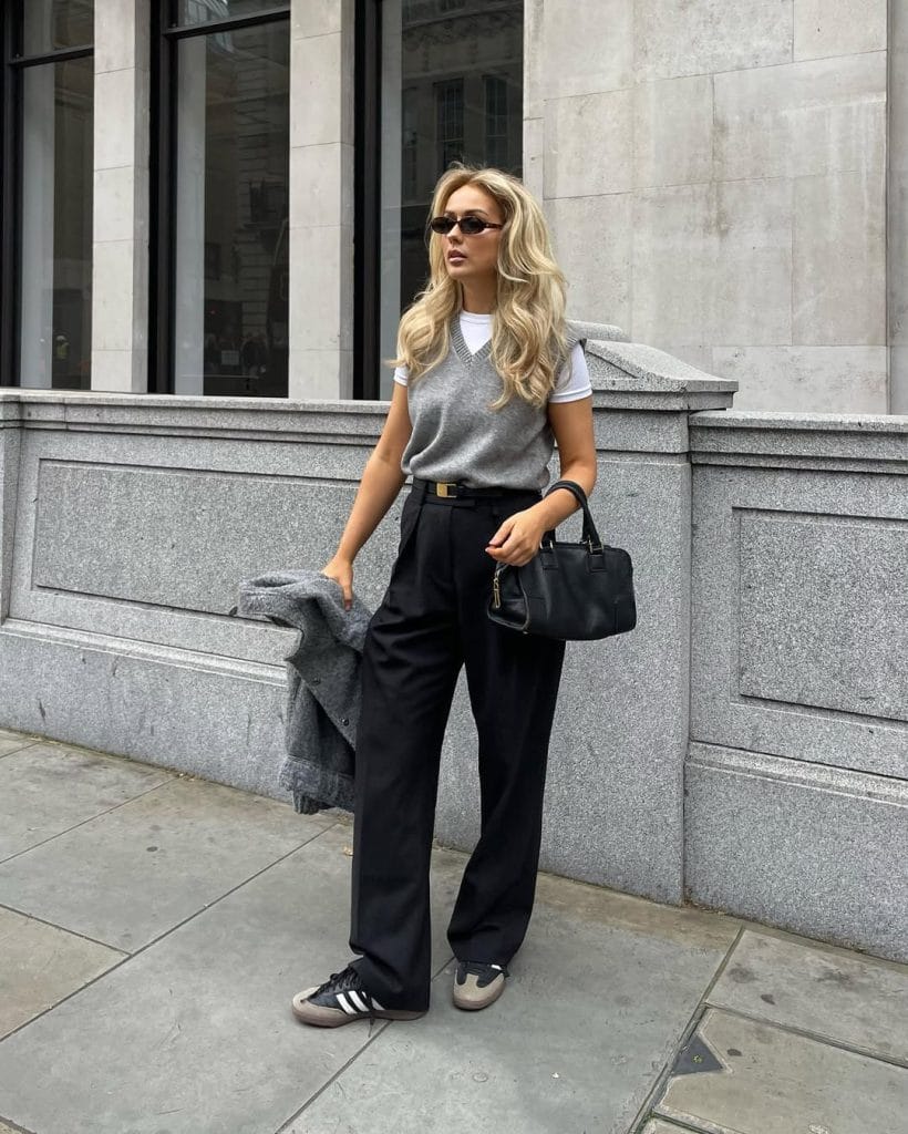 Casual fall work outfit with gray sleeveless vest, white t-shirt, black wide-leg trousers and sneakers for office style