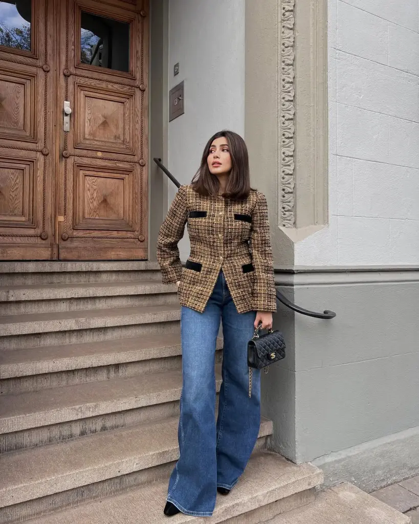 Elegant fall outfit with brown tweed blazer, black trim details, wide-leg blue jeans, black pointed boots and quilted chain bag
