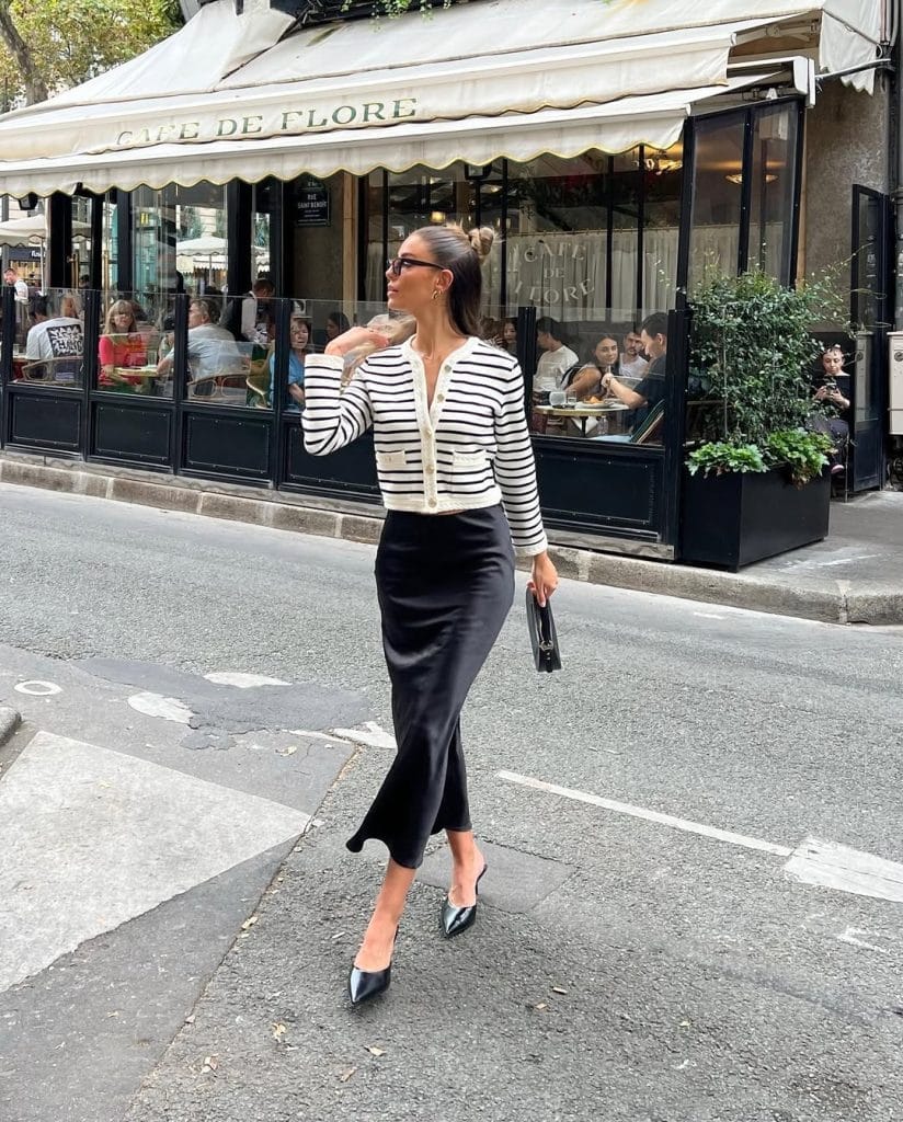Chic Parisian fall outfit with striped cardigan, black midi skirt, pointed heels
