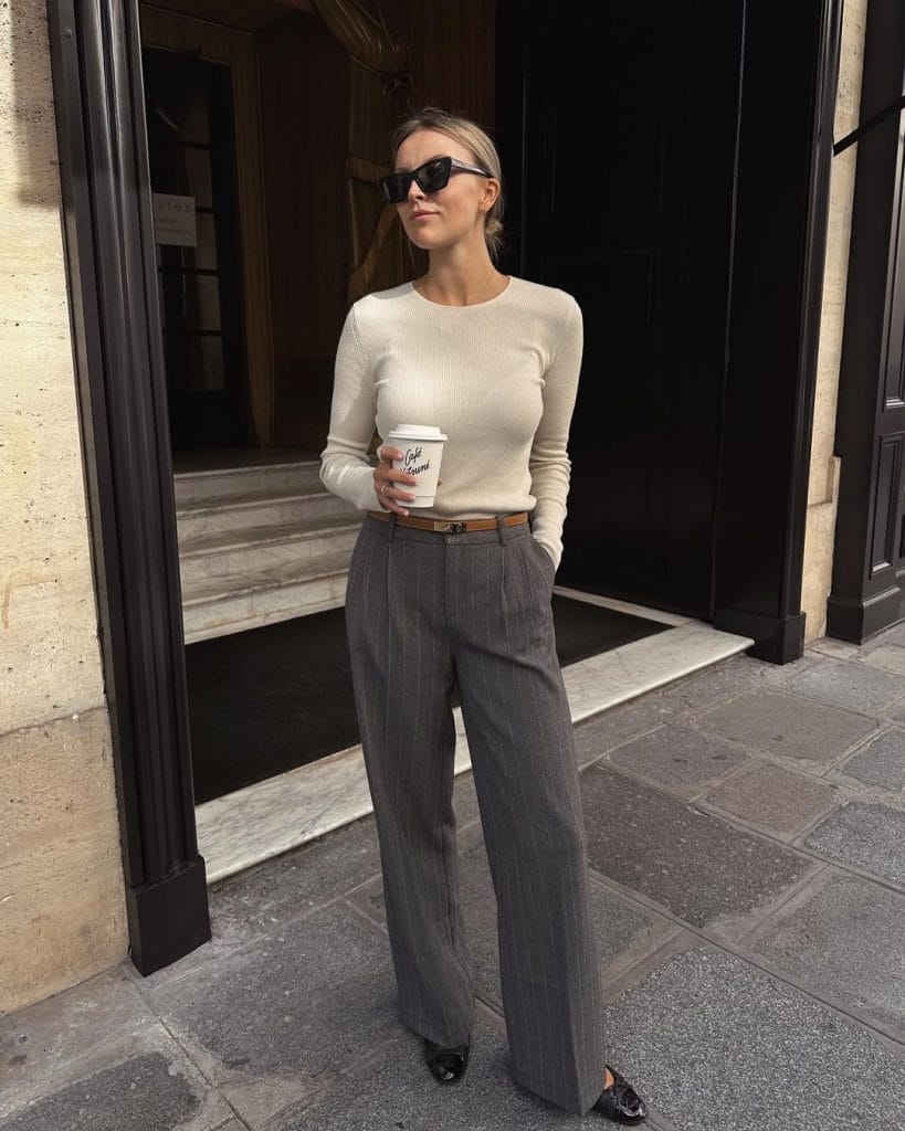 Professional fall work outfit with beige ribbed sweater, gray pinstripe trousers, brown belt and black loafers for office style