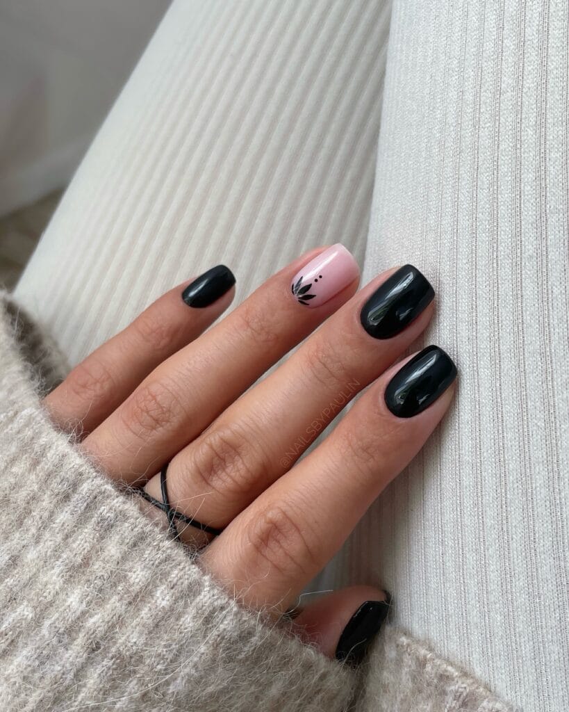 Short black fall nails with one blush-pink accent and a small black leaf design.