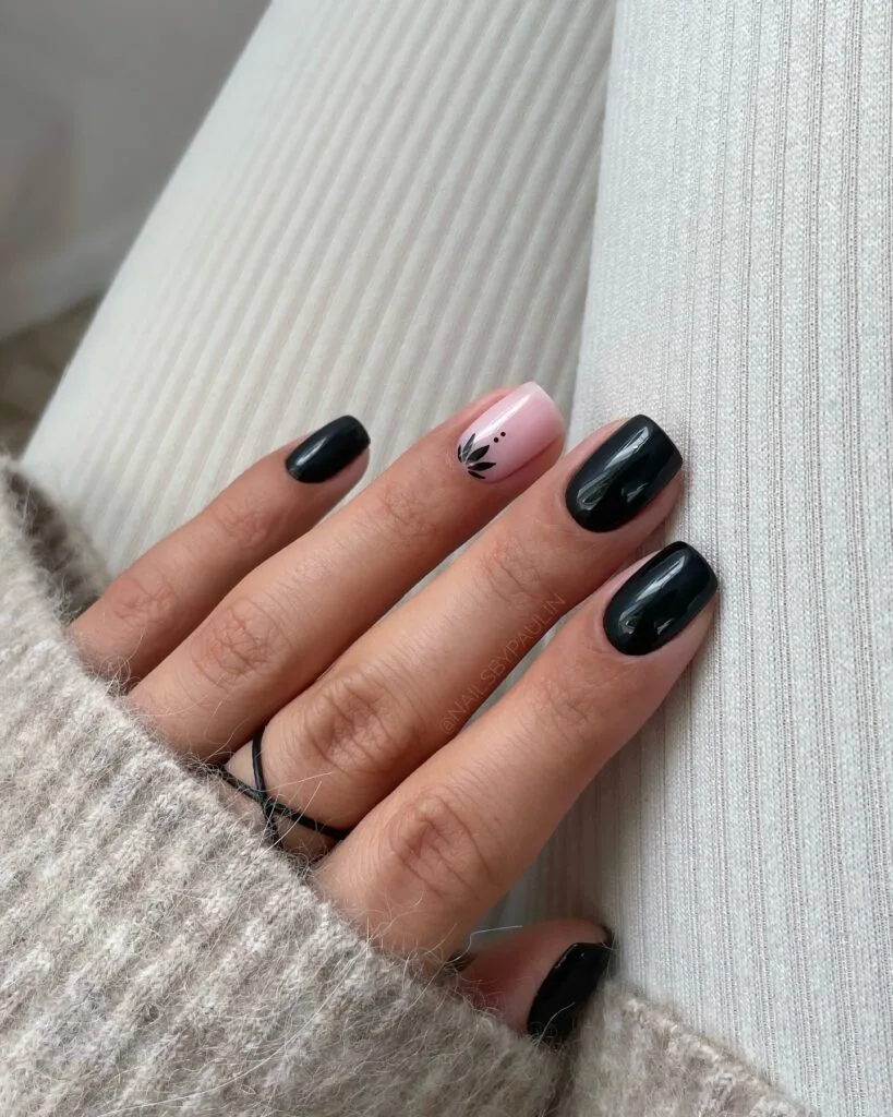 Short black fall nails with one blush-pink accent and a small black leaf design.