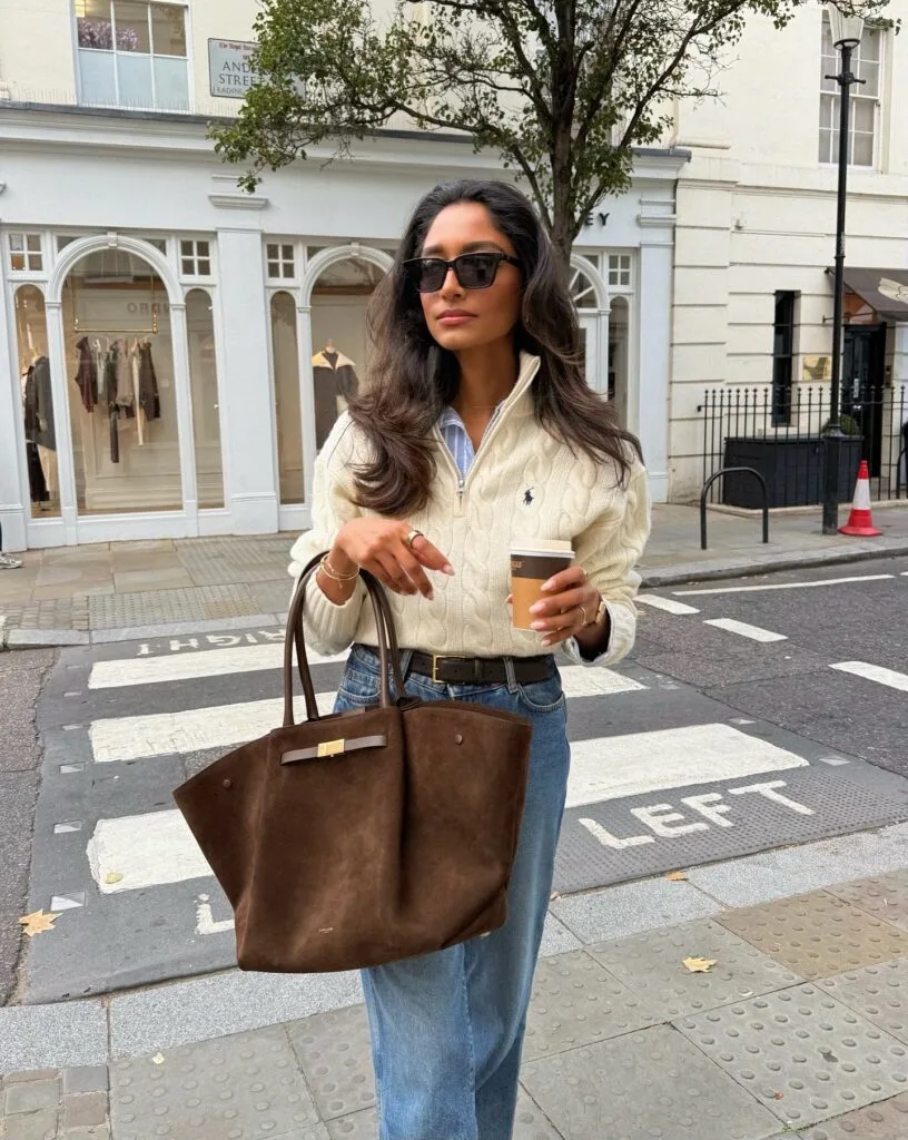 classy autumn outfit with cream cable-knit quarter-zip, striped shirt, jeans and brown suede tote