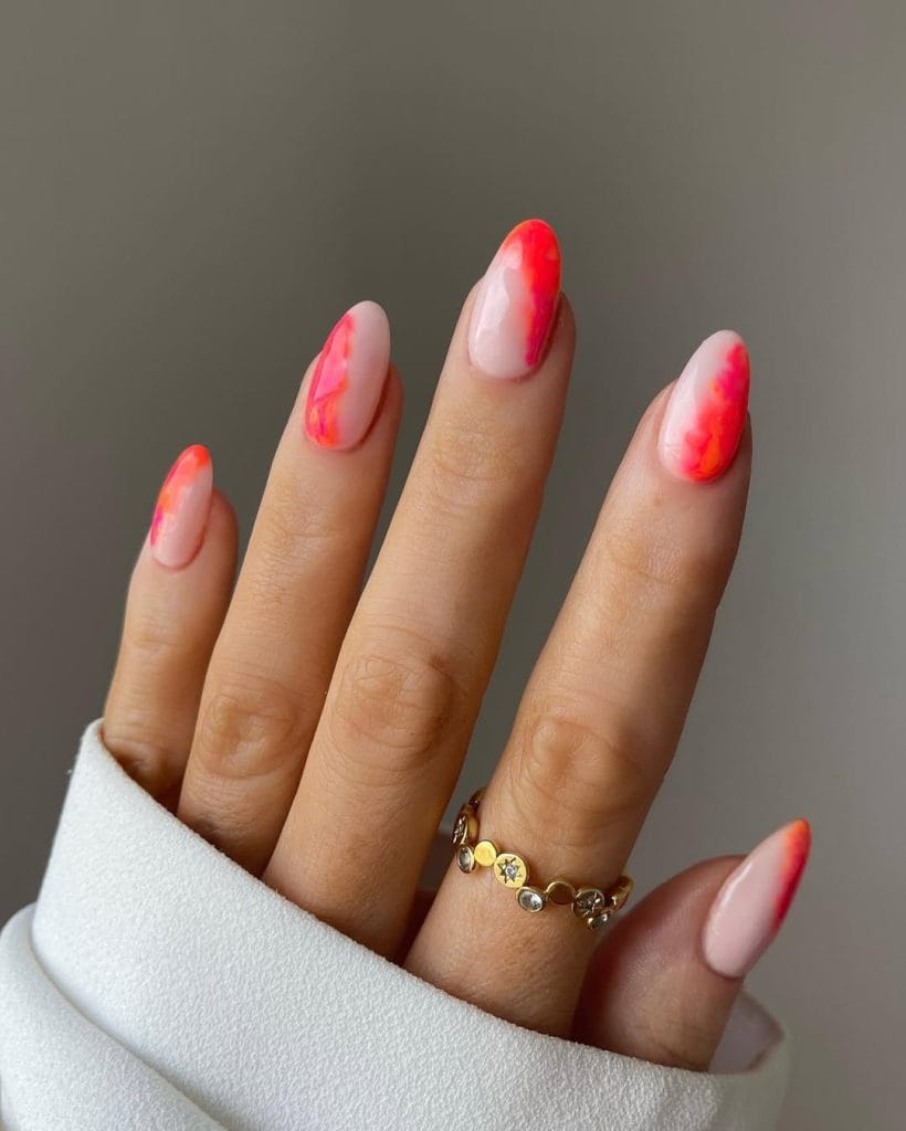 Medium almond August nails with nude base and bright coral marble effect