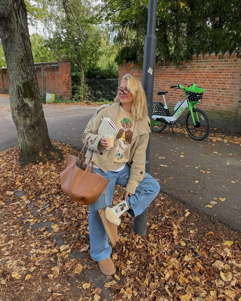 Fall outfit with cropped beige trench, teddy-bear sweater, jeans, tan UGGs, and large tan tote.
