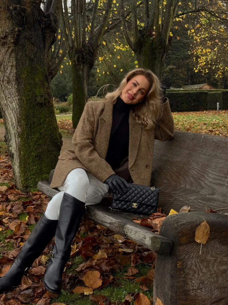 old money fall outfit with camel tweed blazer, black turtleneck, white breeches and tall riding boots