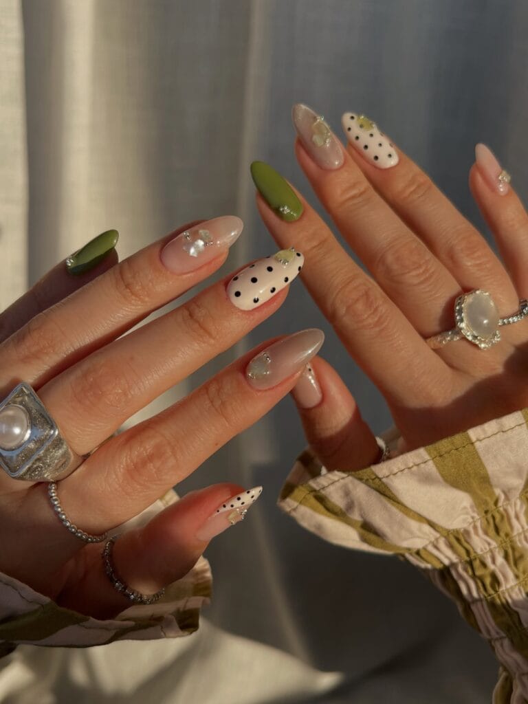 Classy fall nails in olive, nude, and cream with black polka dots, pearly pieces, and tiny silver beads.