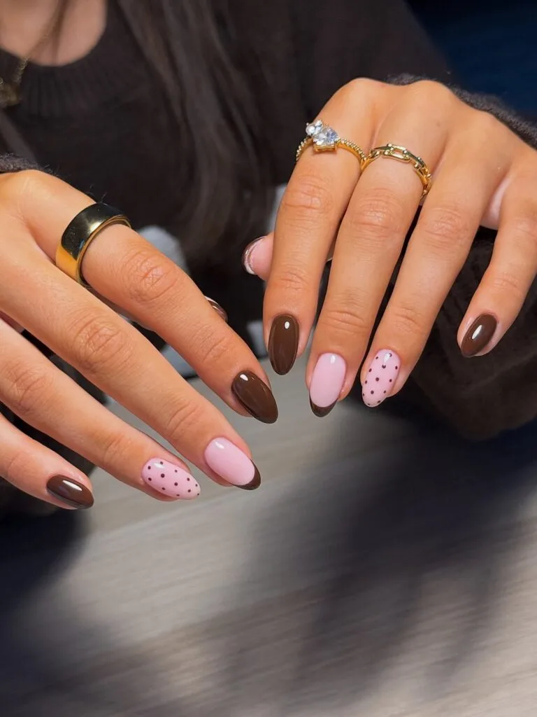 Pink and brown fall nails with chocolate polish, brown French tips, and a pink accent with brown polka dots
