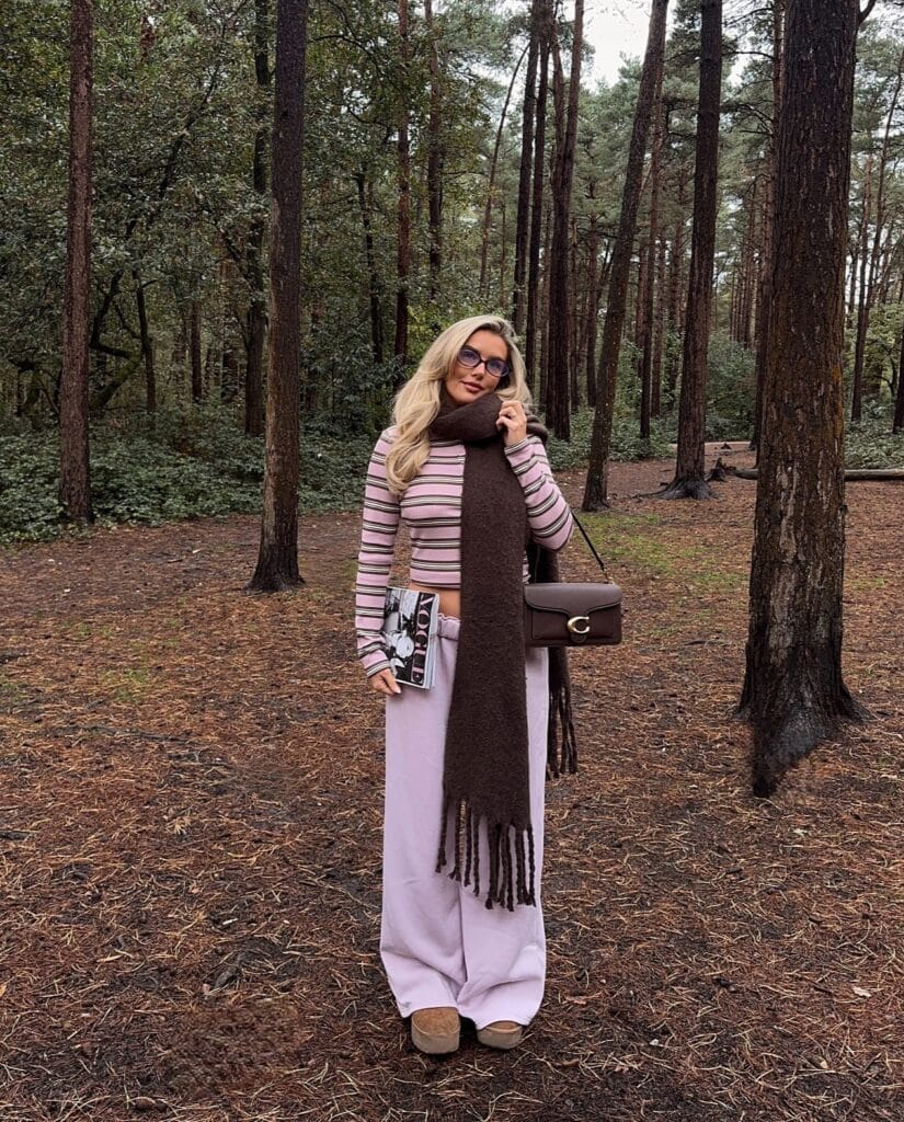 Cozy fall outfit with striped top, pink wide-leg sweatpants, oversized brown scarf, and tan UGGs.

