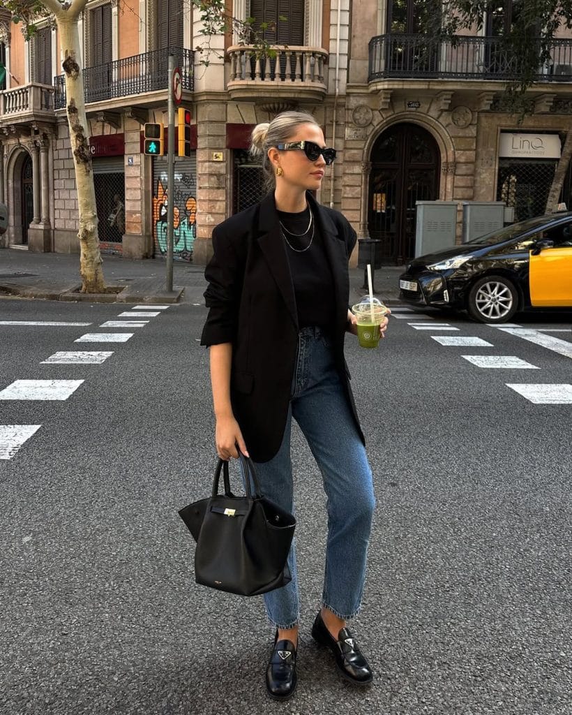 Chic fall work outfit with black oversized blazer, black turtleneck, blue jeans and black loafers for corporate style