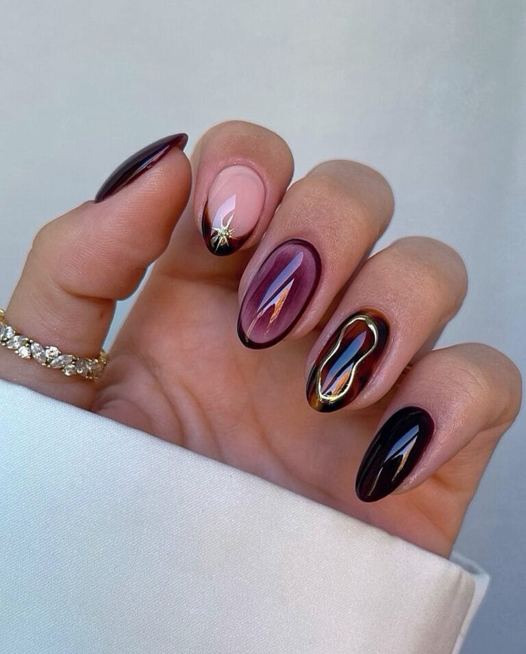 Almond fall nails with tortoiseshell, burgundy borders, a gold star, and a raised gold outline.
