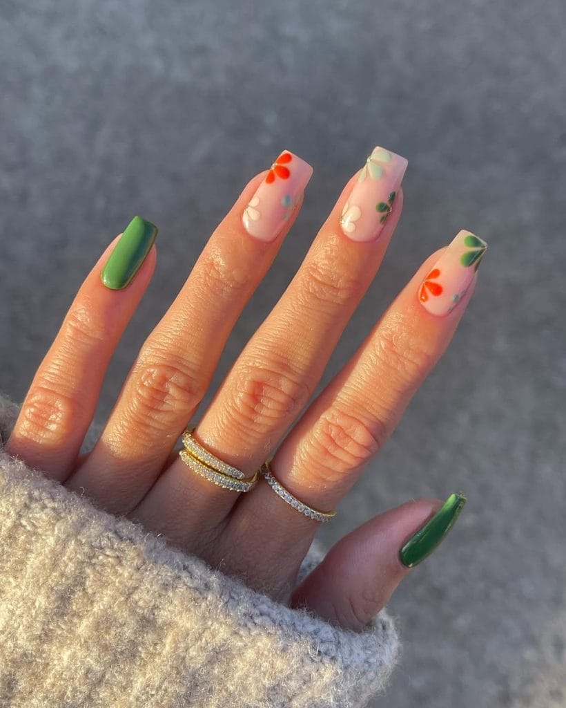 September nails with green polish and floral designs on milky base