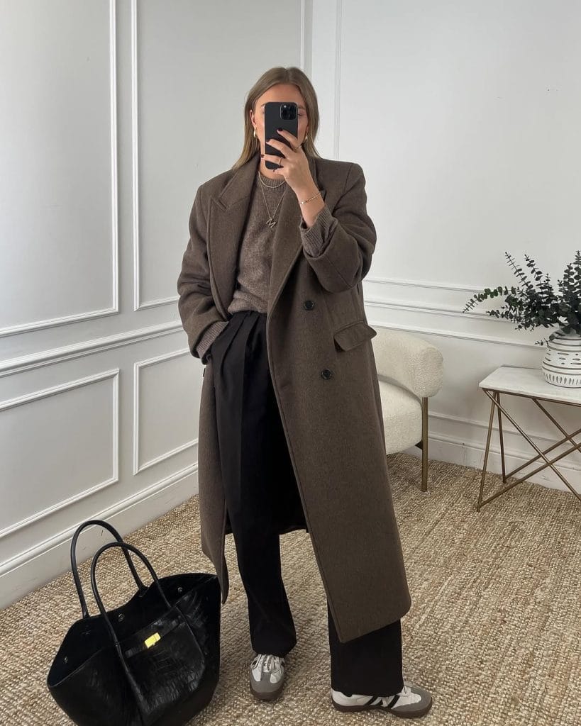 Sophisticated fall work outfit with long brown coat, matching sweater, black trousers and sneakers