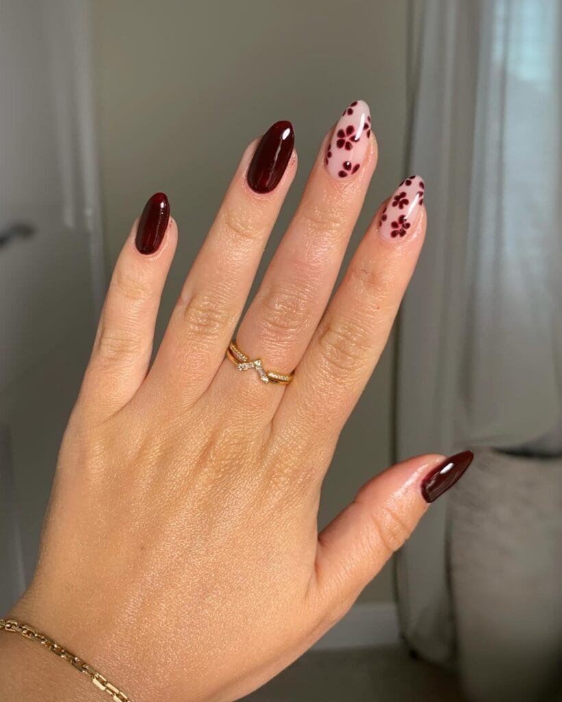 Classy fall nails with glossy burgundy solids and burgundy flowers over pink almond-shaped accents.