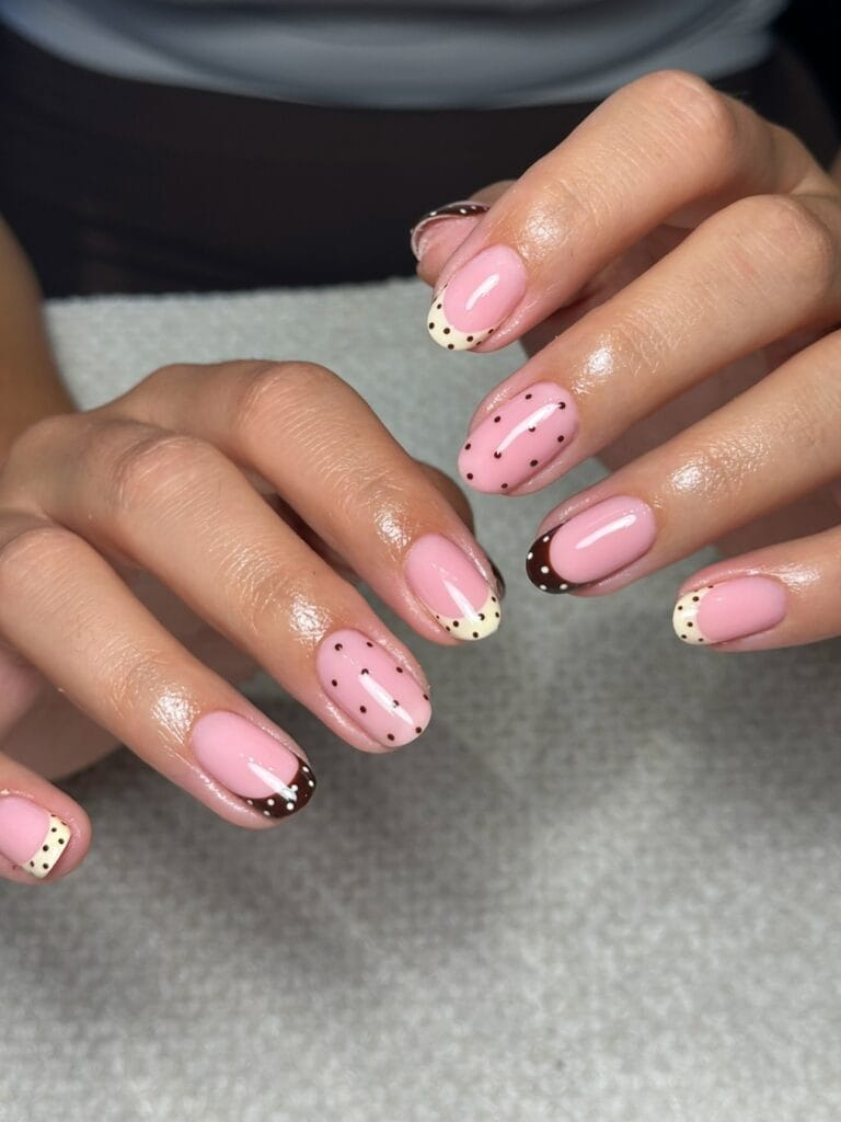 Short oval fall nails with pink bases, cream and chocolate French tips, and contrasting polka dots.