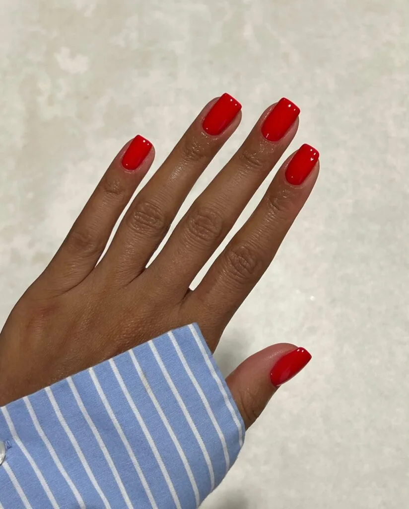 Glossy bright red nails with short square tips for a classic fall manicure.
