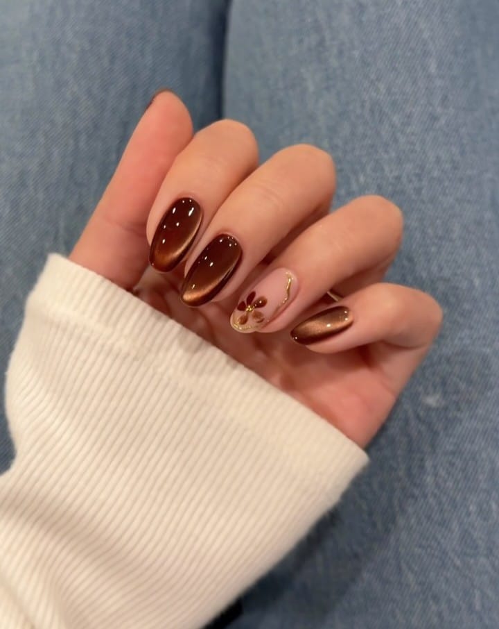 Brown fall nails with copper cat-eye shimmer and a nude accent nail with a burgundy flower and gold swirl