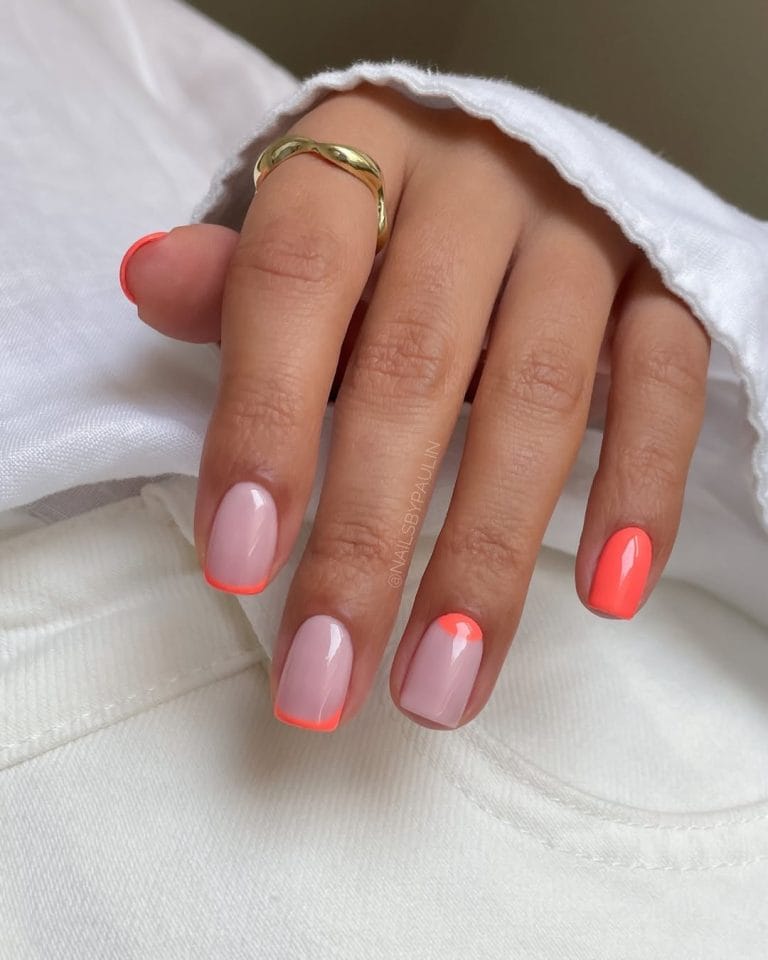 Short summer nails with milky base featuring coral French tips, half-moon design, and solid coral accent