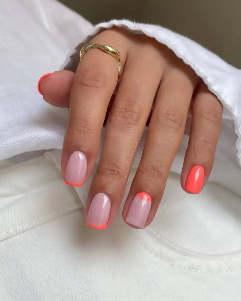 Short summer nails with milky base featuring coral French tips, half-moon design, and solid coral accent