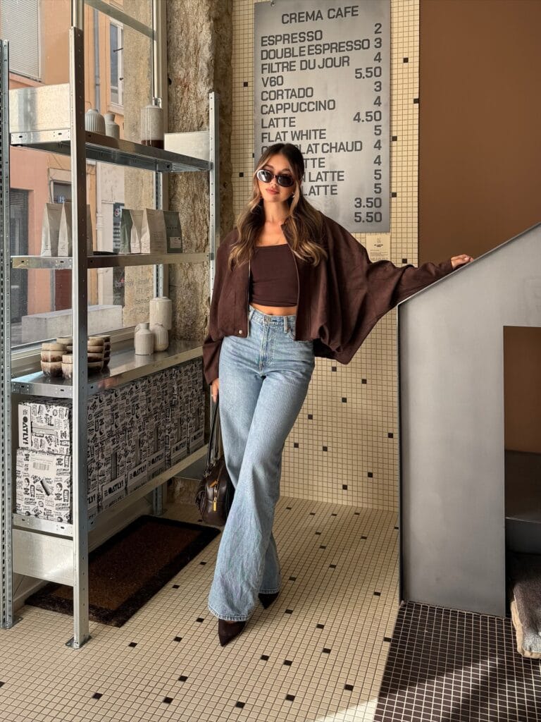 Casual fall outfit with brown suede bomber, brown crop top, light wash wide-leg jeans, and pointed heels