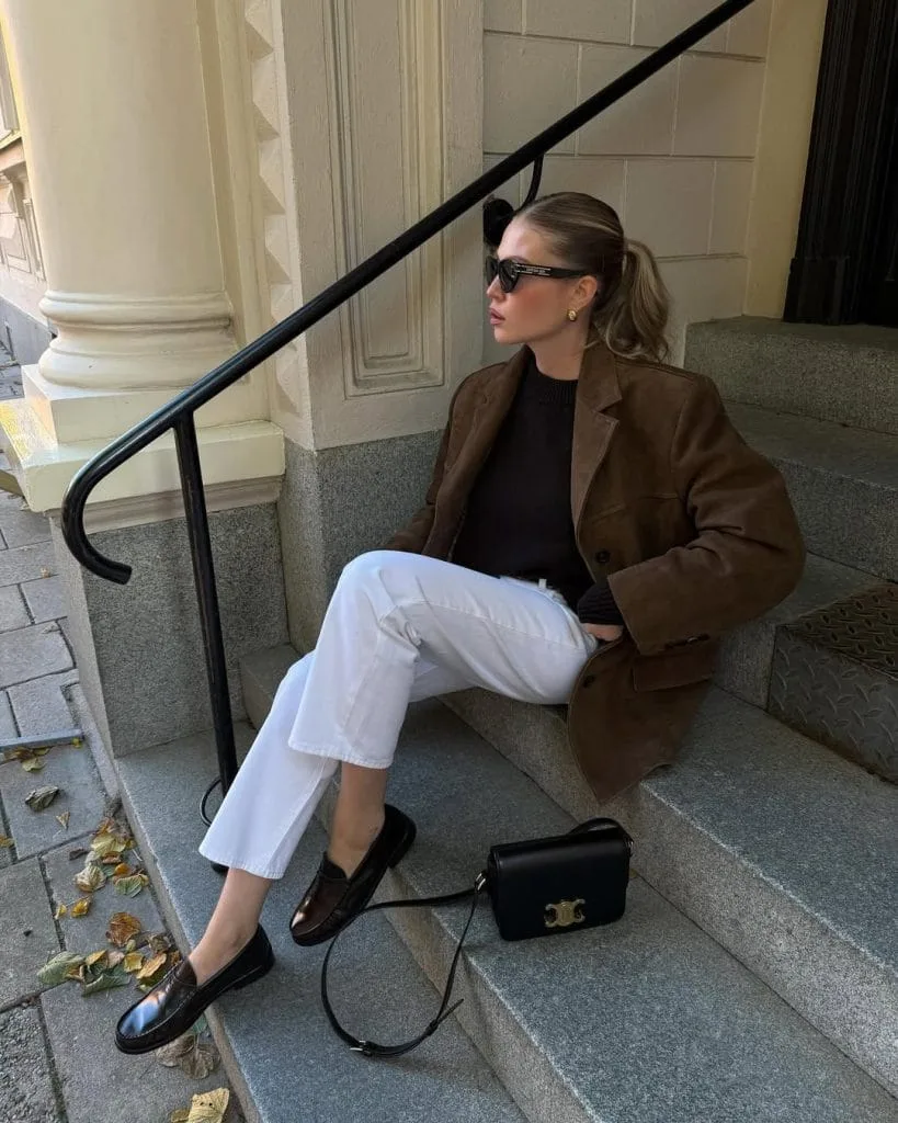 Sophisticated old money outfit with brown blazer, black sweater, white jeans and loafers