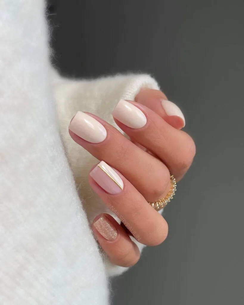 neutral nails in creamy nude short square with gold glitter accent and half sheer gold line detail