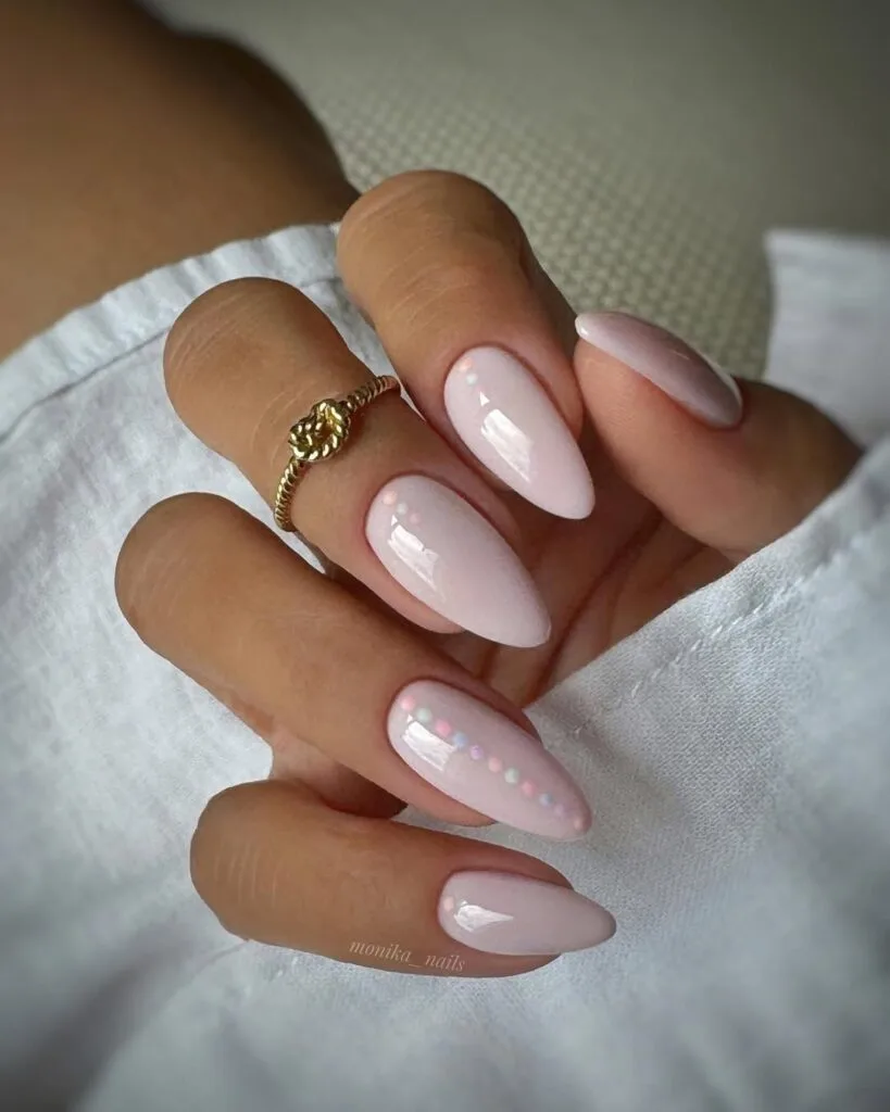 neutral nails in sheer nude pink almond shape with tiny opalescent dot accents