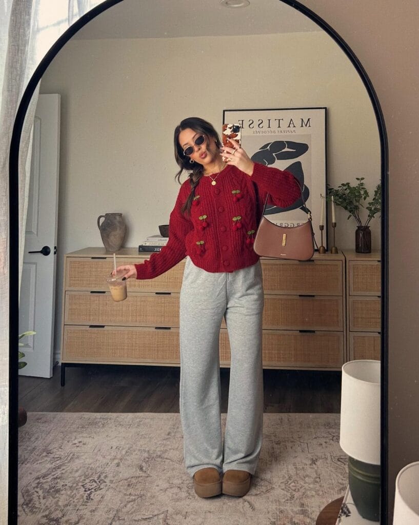 Cozy fall outfit with burgundy cable knit sweater featuring cherry embroidery, gray sweatpants and tan platform Uggs
