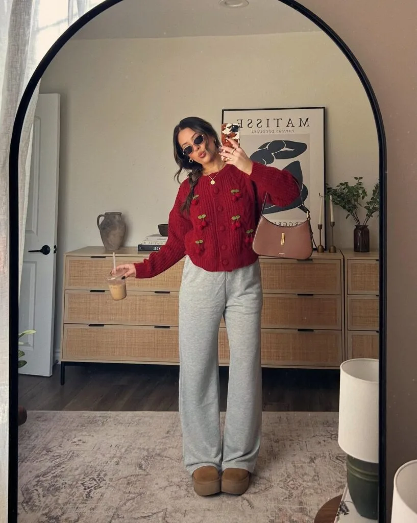 Cozy fall outfit with burgundy cable knit sweater featuring cherry embroidery, gray sweatpants and tan platform Uggs
