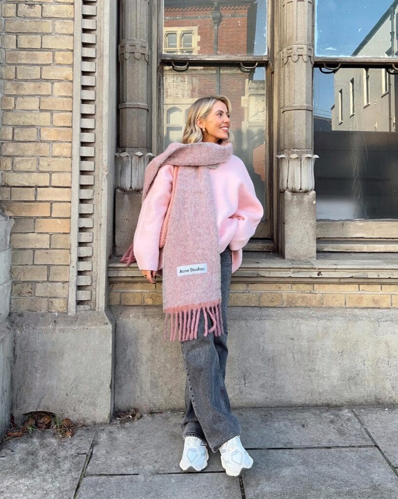 Cozy fall outfit in pink oversized sweater with matching Acne Studios scarf, gray jeans and white chunky sneakers