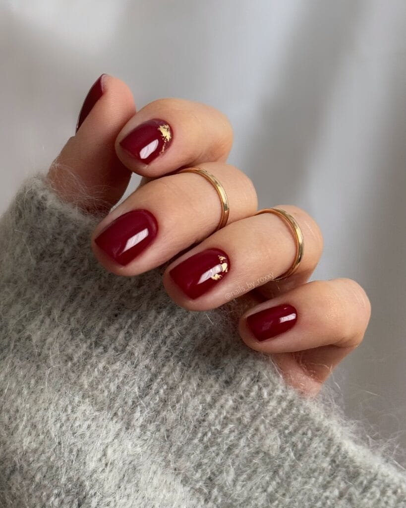 Short burgundy nails with gold foil accents, classy nail design