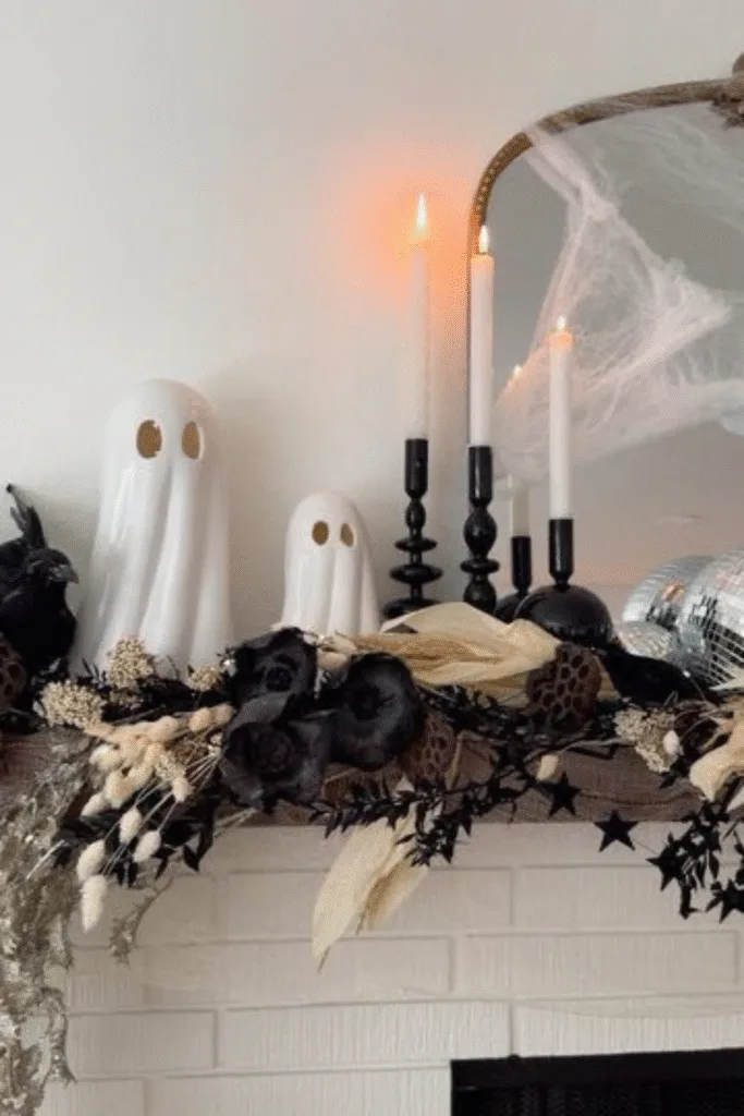 Halloween decorations on white mantel with ghost figures and dried flowers
