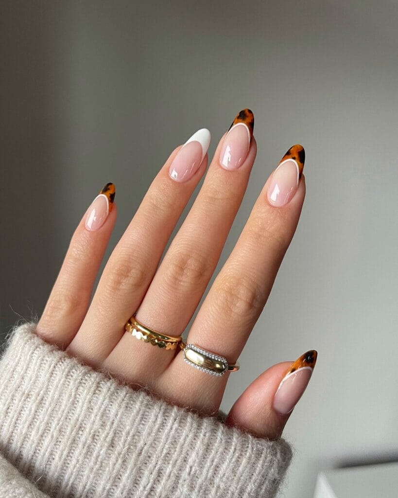 almond nails with pink base, tortoiseshell tips, and one white French tip, fall nail design