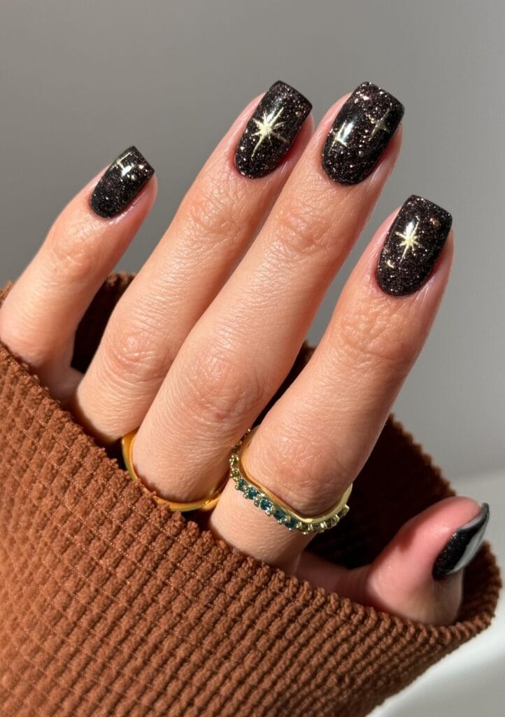 short square nails with black glitter polish and gold star design, October nails