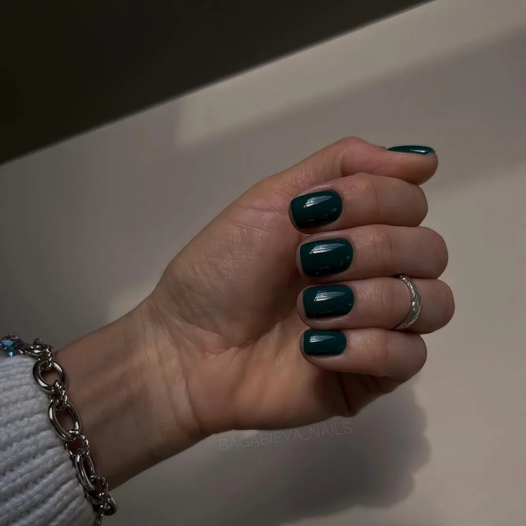 Short round nails in glossy dark green polish
