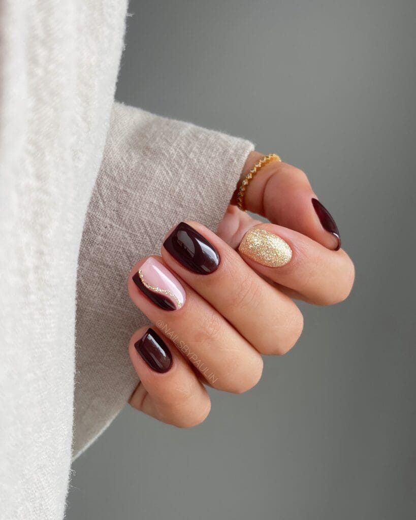 short nails with burgundy polish, gold glitter accent, and gold swirl nail art, October nail ideas