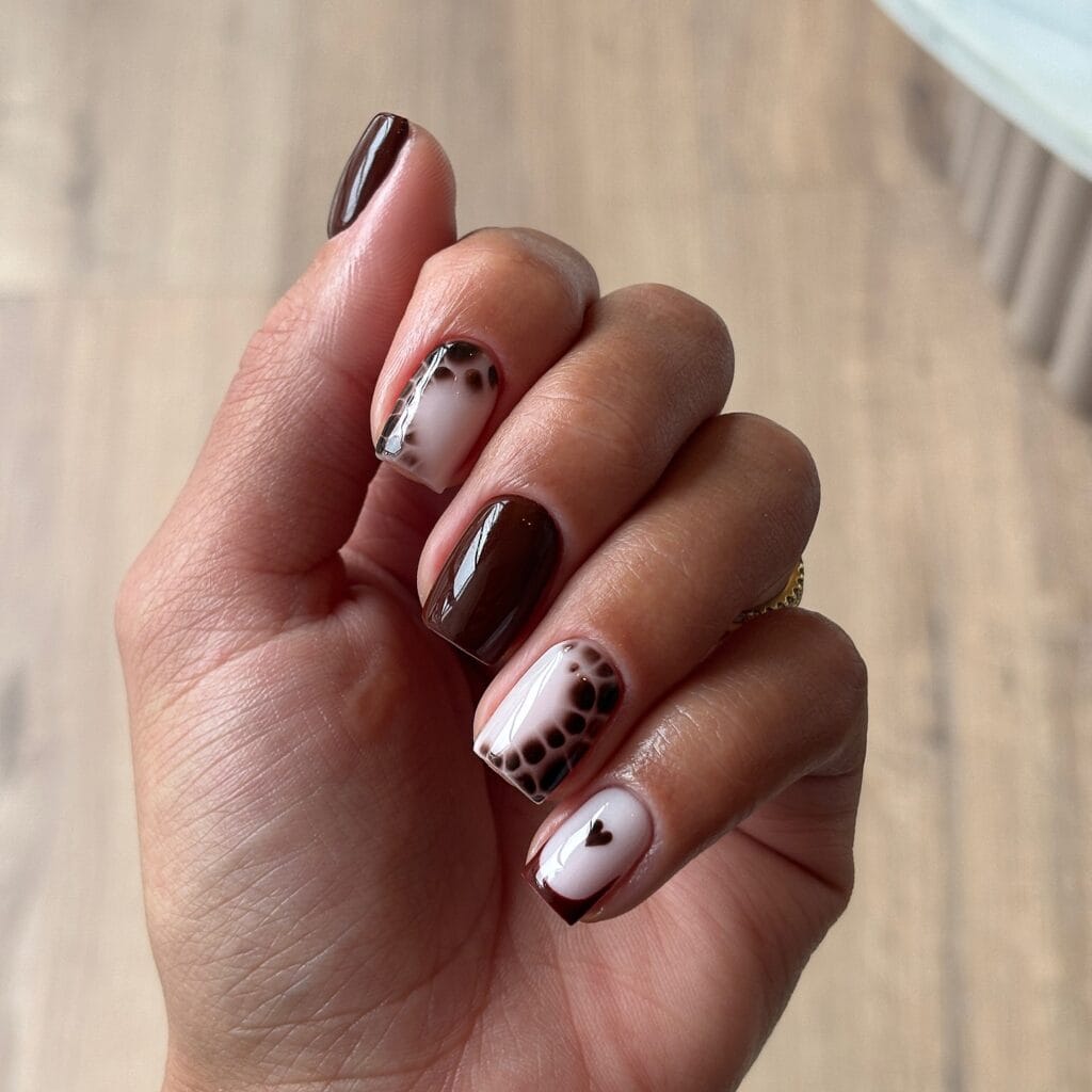 short nails with chocolate brown polish, snake pattern accents, and heart detail, fall nail design
