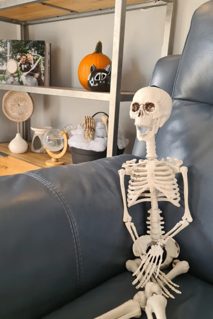 Small skeleton Halloween decoration sitting on gray couch