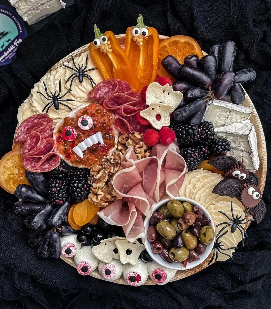 Halloween charcuterie board with bell pepper pumpkins and cookie spiders
